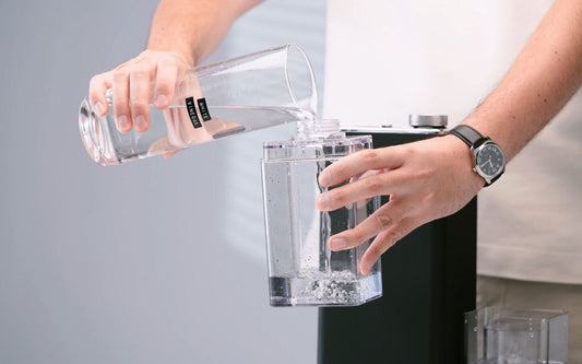 Remplissage du réservoir d’un défroisseur vertical SteamOne avec du vinaigre blanc pour un détartrage efficace et naturel.