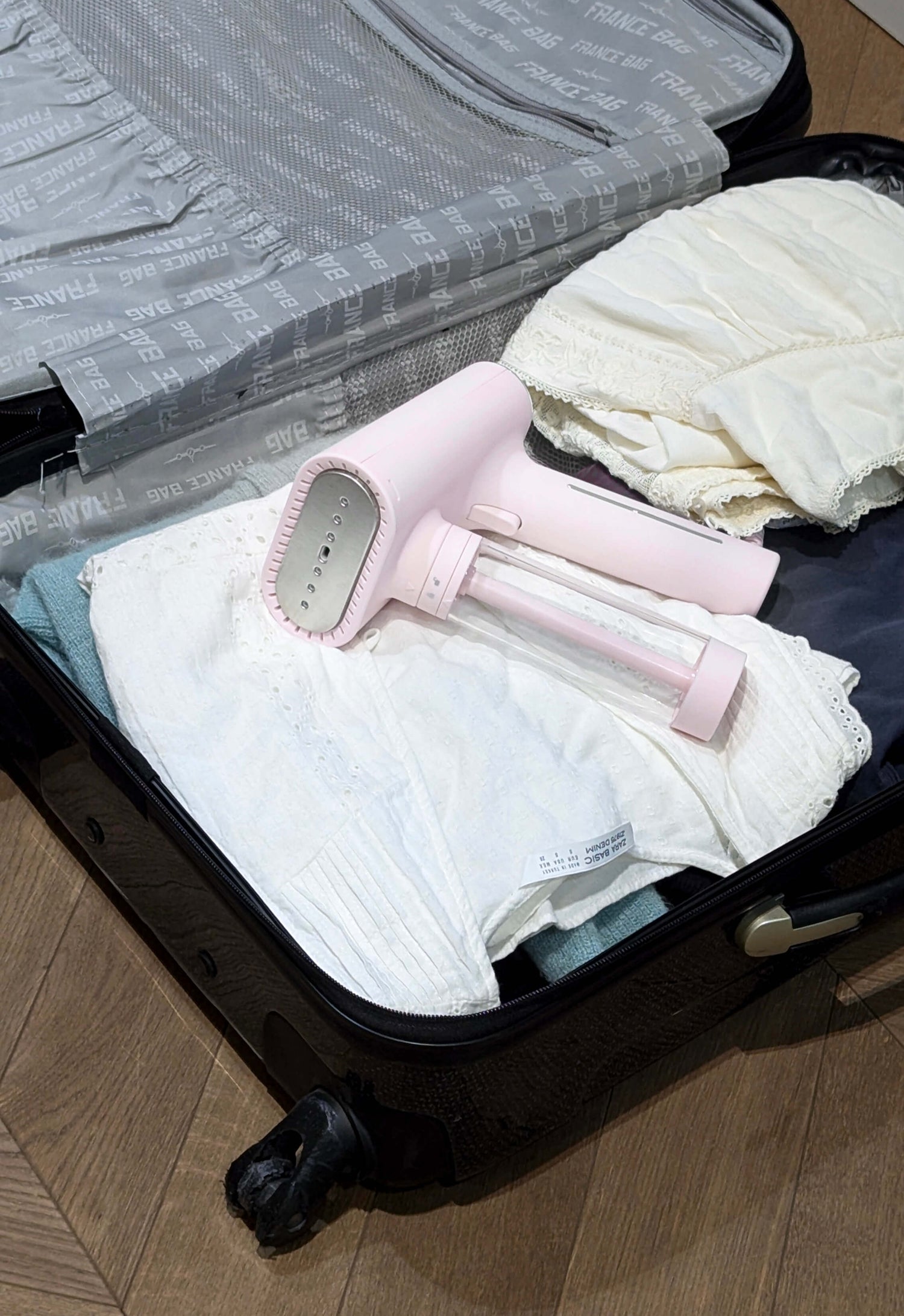 Défroisseur vapeur rose SteamOne Karl rose dans une valise, idéal pour les voyages et vêtements sans plis.